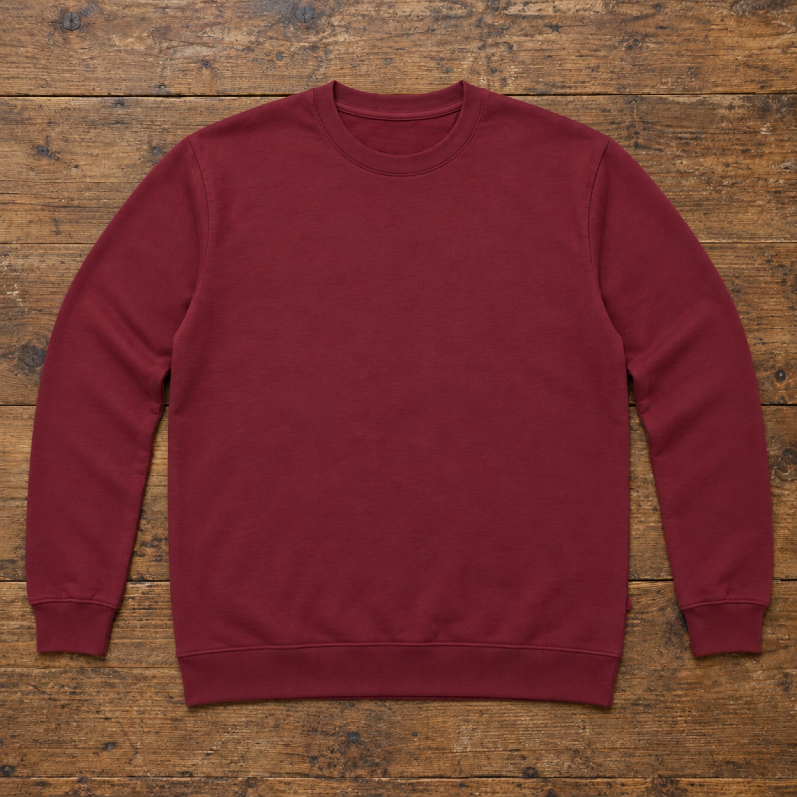 Sudadera granate lisa doblada sobre una mesa de madera